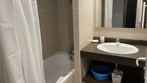 Un bagno con una vasca, un lavandino, uno specchio e una bacinella blu.