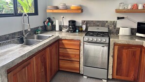 Una cocina con armarios de madera, un lavamanos de acero inoxidable, una estufa y un microondas.