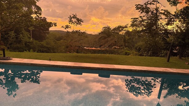 Una piscina con borde de azulejos y un reflejo claro de árboles y cielo.