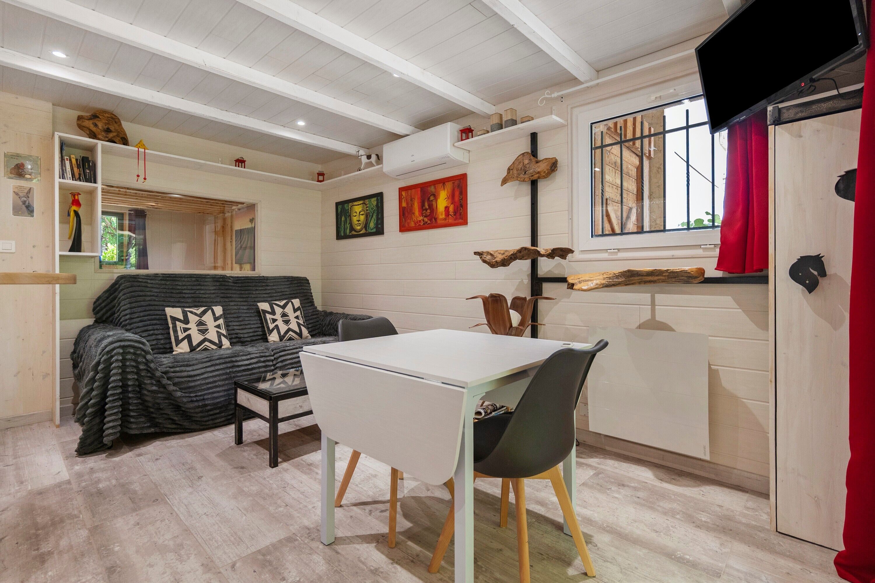 Un espacio habitable compacto con sofá, mesa de comedor y área de cocina.