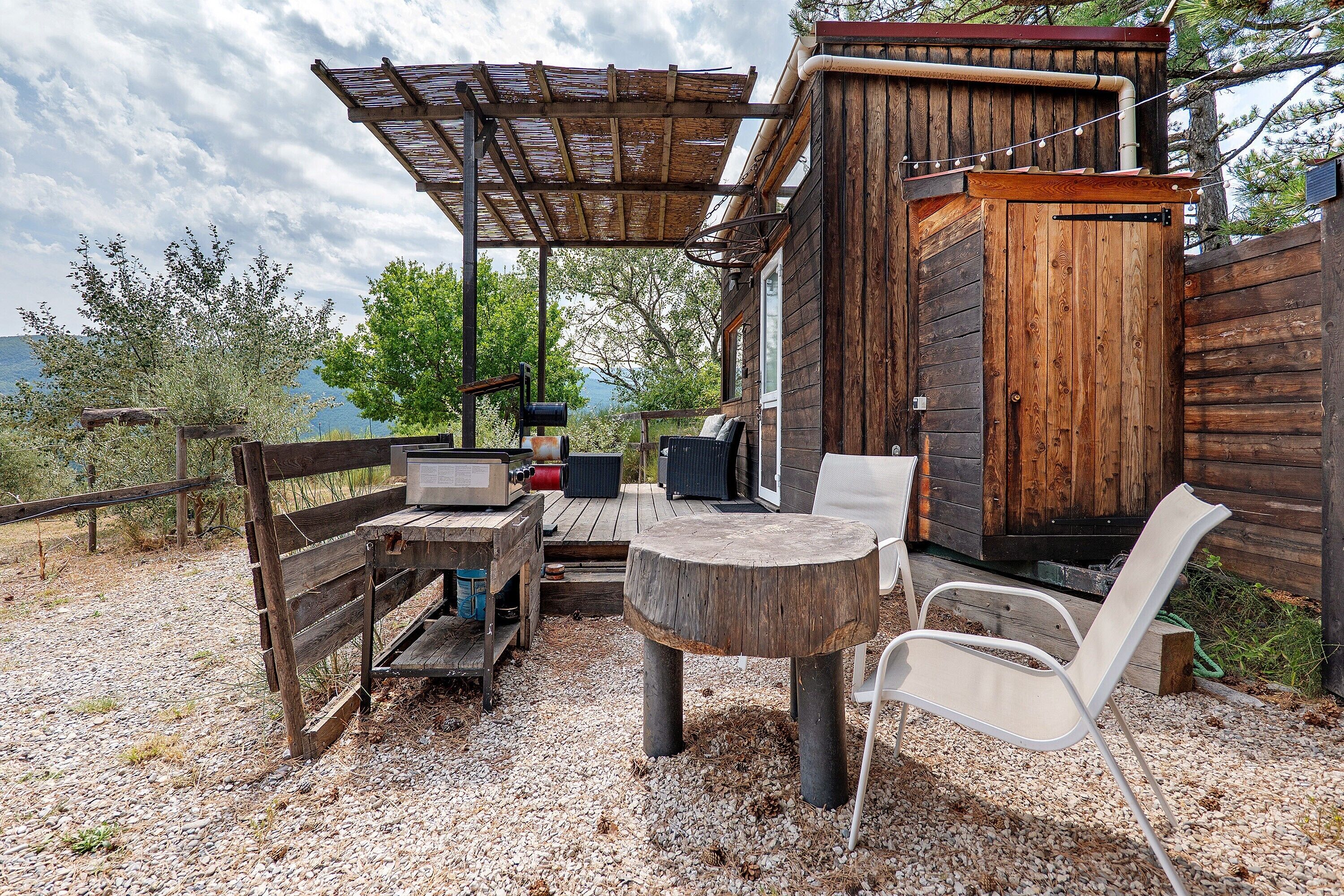 Un espace extérieur aménagé dans un style rustique, avec une table en bois, des chaises et une structure en forme de pergola.