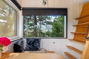 Una habitación con ventana, una escalera de madera y una cama con cabecera negra.