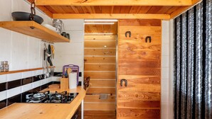 Una cocina funcional con armarios de madera, estufa a gas y un colgador para ollas.