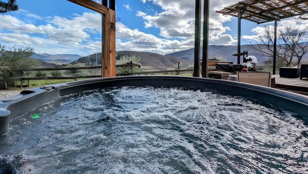 Un jacuzzi con cubierta de madera y vista a las montañas.