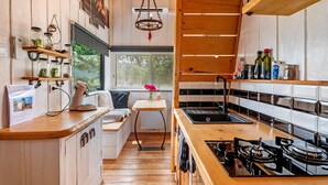 Una cocina compacta con armarios de madera, estufa integrada y ventana con vistas a la vegetación.