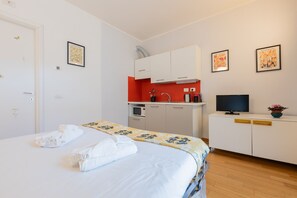 A hotel room with a bed, a kitchenette, a television, and artwork on the walls. - Priocca Mono 001 by Wonderful Italy (Turin)