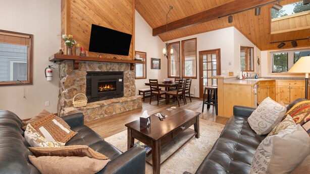 A spacious living room with a stone fireplace, leather sofas, and a wooden ceiling. - 3BR Cozy Townhome | Walk to Town | Office, Patio (Winter Park)