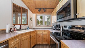 A modern kitchen with wooden cabinets, a stainless steel stove, and a large window. - 3BR Cozy Townhome | Walk to Town | Office, Patio (Winter Park)