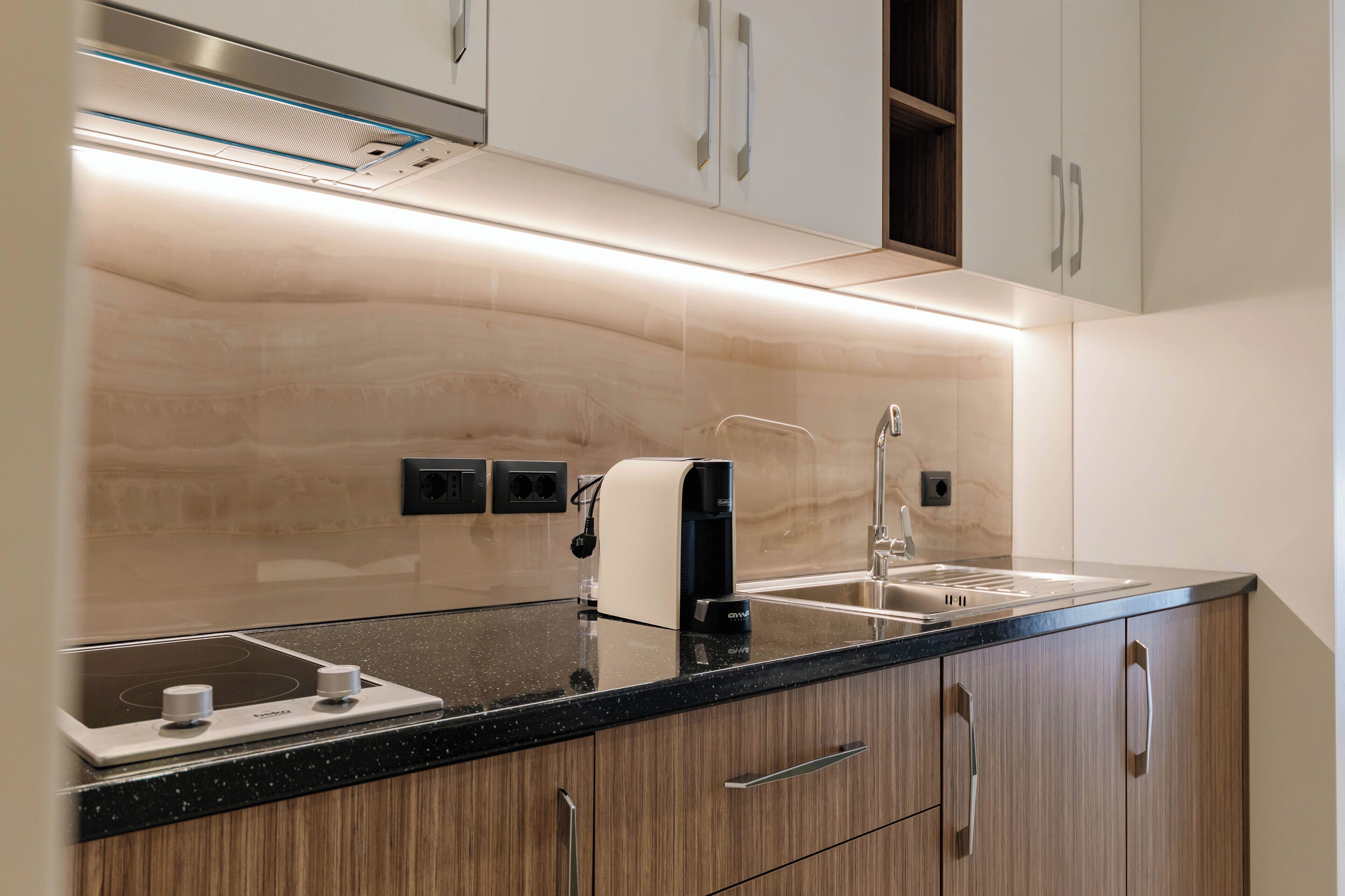 A modern kitchen with a black countertop, stainless steel appliances, and wooden cabinets.