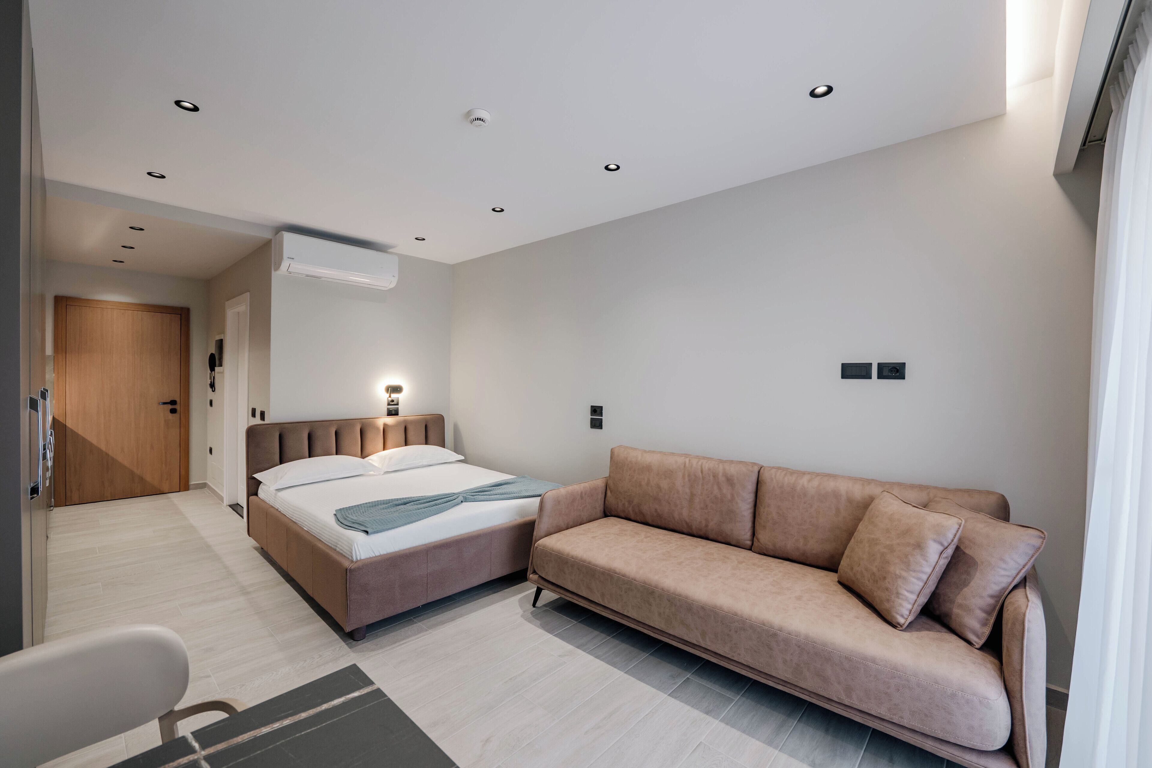 A modern bedroom with a bed, a sofa, and a desk.