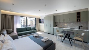 A modern hotel room with a large bed, a sofa, a dining table, and a kitchen area. - Blas Residence (Sarande)