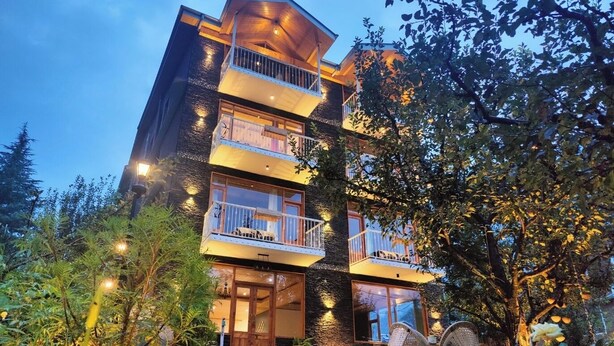 A multi-story building with balconies, a staircase leading to the entrance, and outdoor seating. - NinYanWays Boutique Stay (Manali)