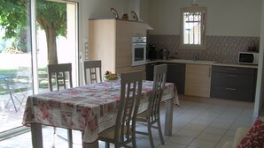 A dining area with a table set for four, a kitchen with modern appliances, and a view of the outdoors.