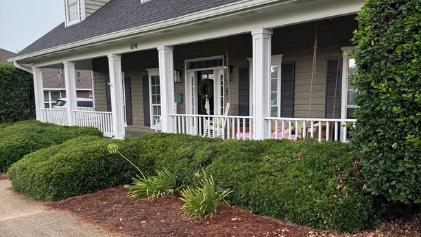 A two-story house with a covered porch, a front door, and a mailbox.
