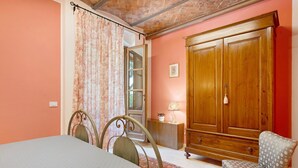 Een slaapkamer met een bed, een stoel, een kledingkast en een kleine tafel met een lamp.