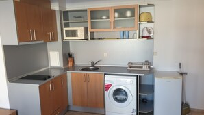A compact kitchen with a built-in washing machine, a microwave, and a coffee maker.