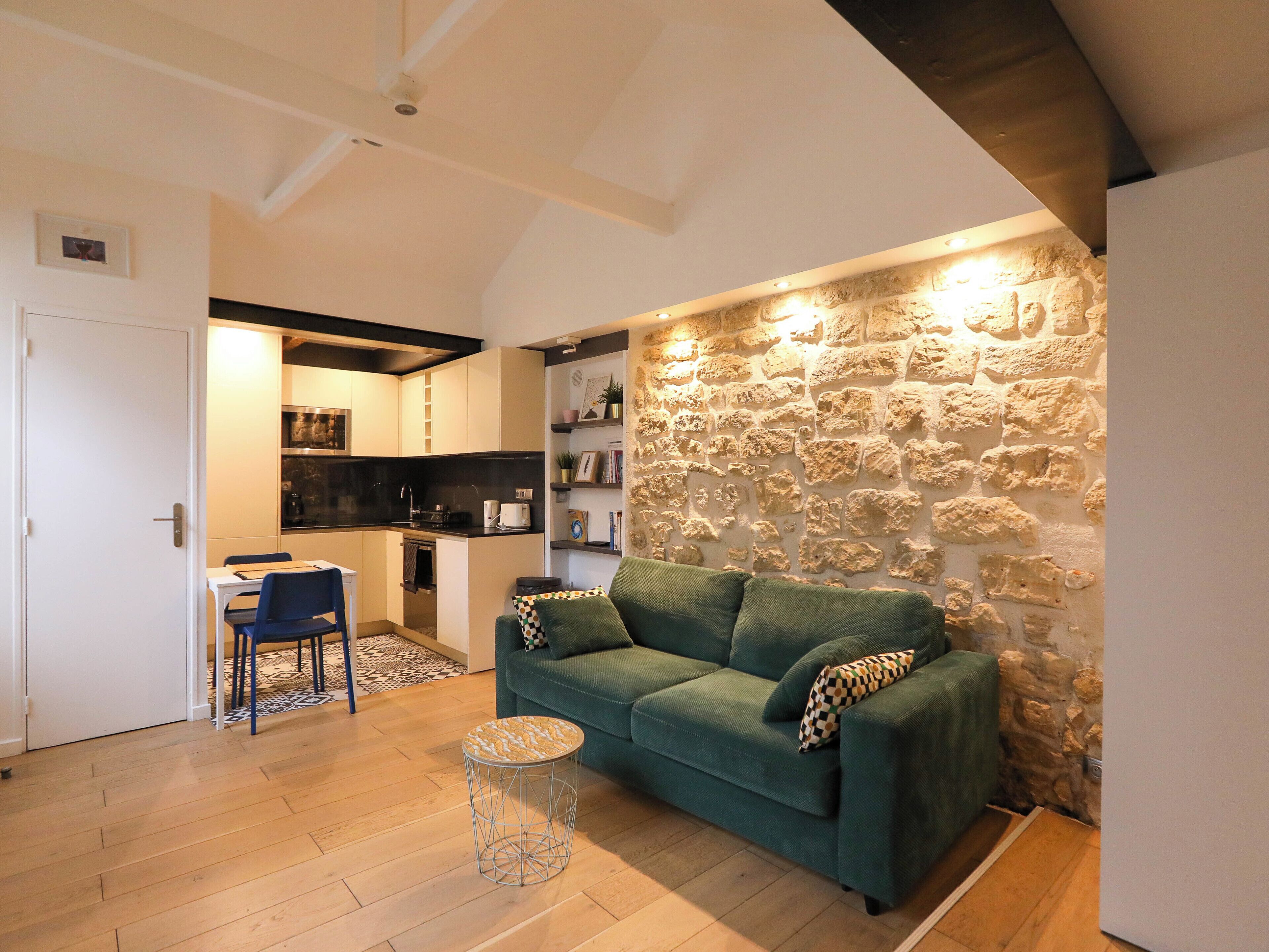 Ein gemütliches Wohnzimmer mit einer Wand aus Stein, einem grünen Sofa und einem runden Couchtisch.