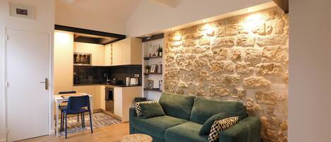 Ein gemütliches Wohnzimmer mit einer Wand aus Stein, einem grünen Sofa und einem runden Couchtisch.