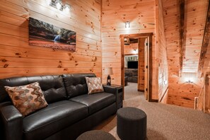 Un interior de madera con un sofá de cuero, una lámpara y un cuadro de una cascada.