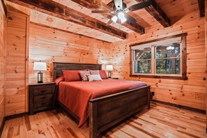 A wooden cabin bedroom with a bed, nightstands, and a window. - Timberland Ridge | Hocking Hills, New, Hot Tub (Logan)
