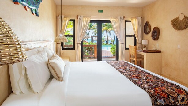 Ein Hotelzimmer mit einem großen Bett, einem Schreibtisch mit Stuhl, einer Wanddekoration und Blick ins Freie.