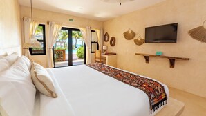 Ein Hotelzimmer mit einem großen Bett, einem an der Wand befestigten Fernseher und einem Balkon mit Vorhängen.