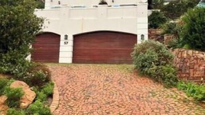Une maison à deux étages avec un garage, une allée pavée et de la verdure tout autour.