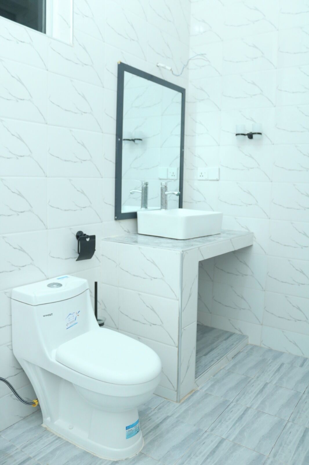 A bathroom with a toilet, sink, and mirror.