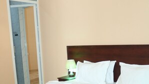 Una cama bien hecha con sábanas blancas y pétalos de flores rosadas sobre el edredón.
