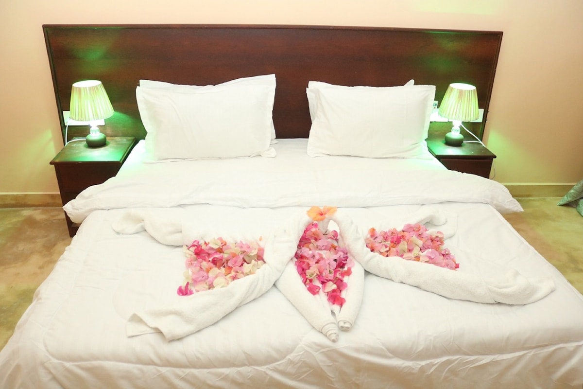 Una cama bien tendida con sábanas blancas y arreglos florales decorativos.