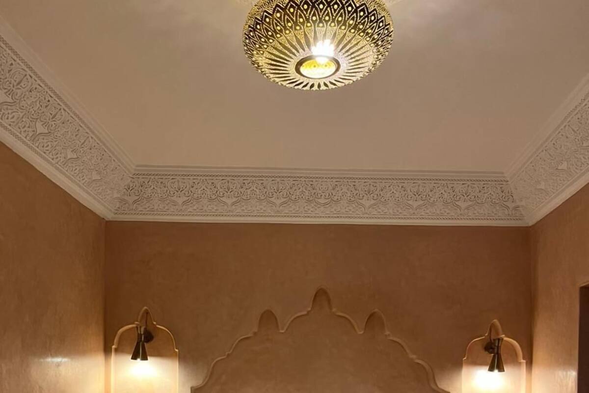A hotel room with a large bed, two wall-mounted lamps, and a decorative ceiling light.