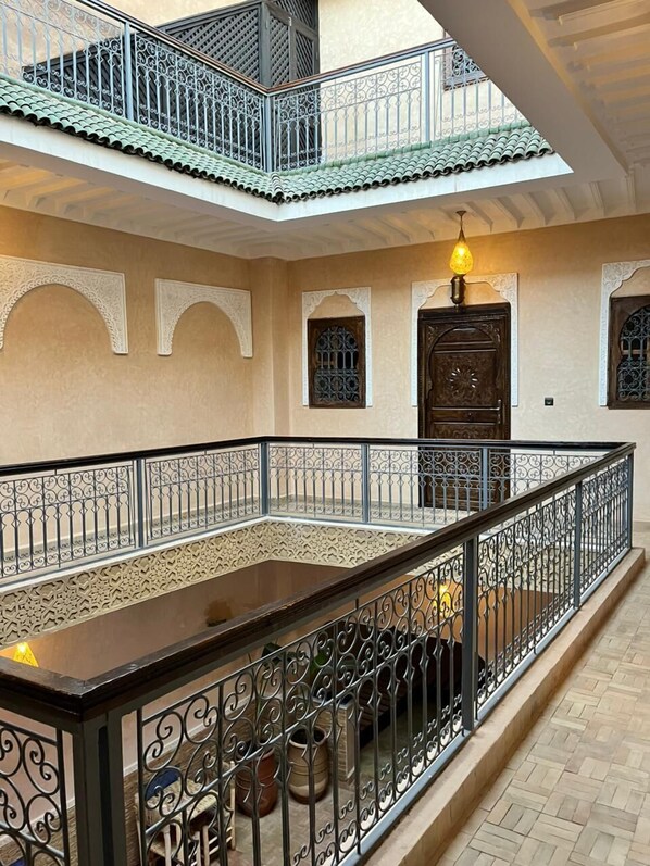 A spacious interior with a central open area, decorative arches, and a balcony with intricate railing. - Dar Hilana Locanda Boutique Collection (Marrakech)