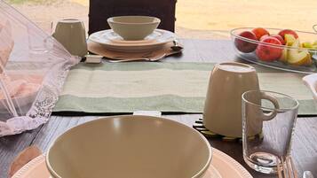 A table set for two with a bowl, plates, cutlery, a glass, and a fruit bowl.