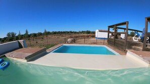 A swimming pool with a wooden deck and a white building in the background.