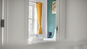 A room with a bed, a window with yellow curtains, a lamp, and a wall with a framed picture. - Drakeway House, Reading (Berkshire)
