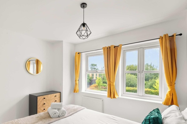 This bright and airy bedroom is perfectly designed to feel both modern and incredibly welcoming, especially with the natural sunlight pouring in through the large windows. The crisp white walls create a clean and spacious atmosphere.