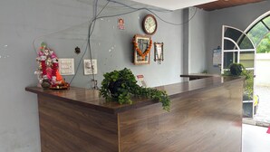 A reception desk with a clock, a framed picture, and a small statue. - Hotel Dhana Lakshmi Bliss (Dewas)