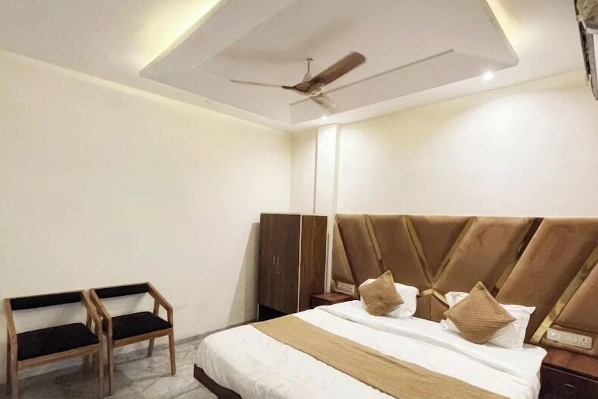 Une chambre d’hôtel moderne avec un grand lit, un ventilateur de plafond et un sol en pierre.