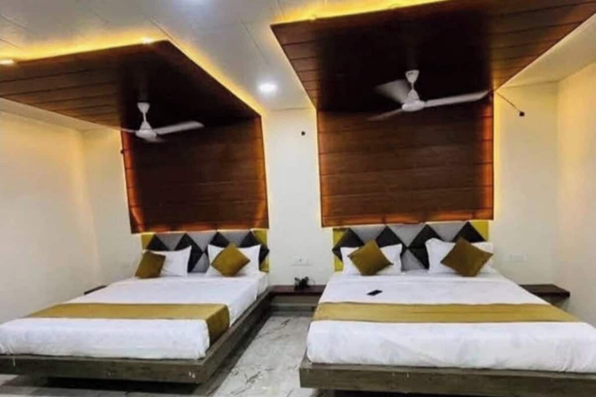 Une chambre d’hôtel avec deux lits, des têtes de lit en bois, des ventilateurs de plafond et un revêtement de sol en marbre.