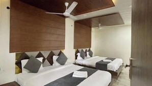 A modern hotel room with two beds, wooden headboards, and a ceiling fan. - Hotel Dhana Lakshmi Bliss (Dewas)