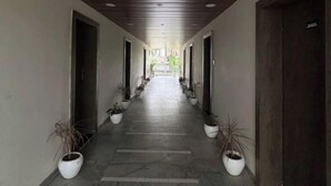 A long, narrow hallway with a wooden ceiling and potted plants on either side. - Hotel Dhana Lakshmi Bliss (Dewas)
