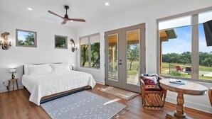 A bedroom with a bed, a ceiling fan, a large window, and a view of the outdoors. - Spacious 12-Bedroom Resort in Graham Texas  - sleeps 40 (Graham)