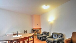 A living room with a fireplace, leather sofas, a dining table with chairs, and a floor lamp.