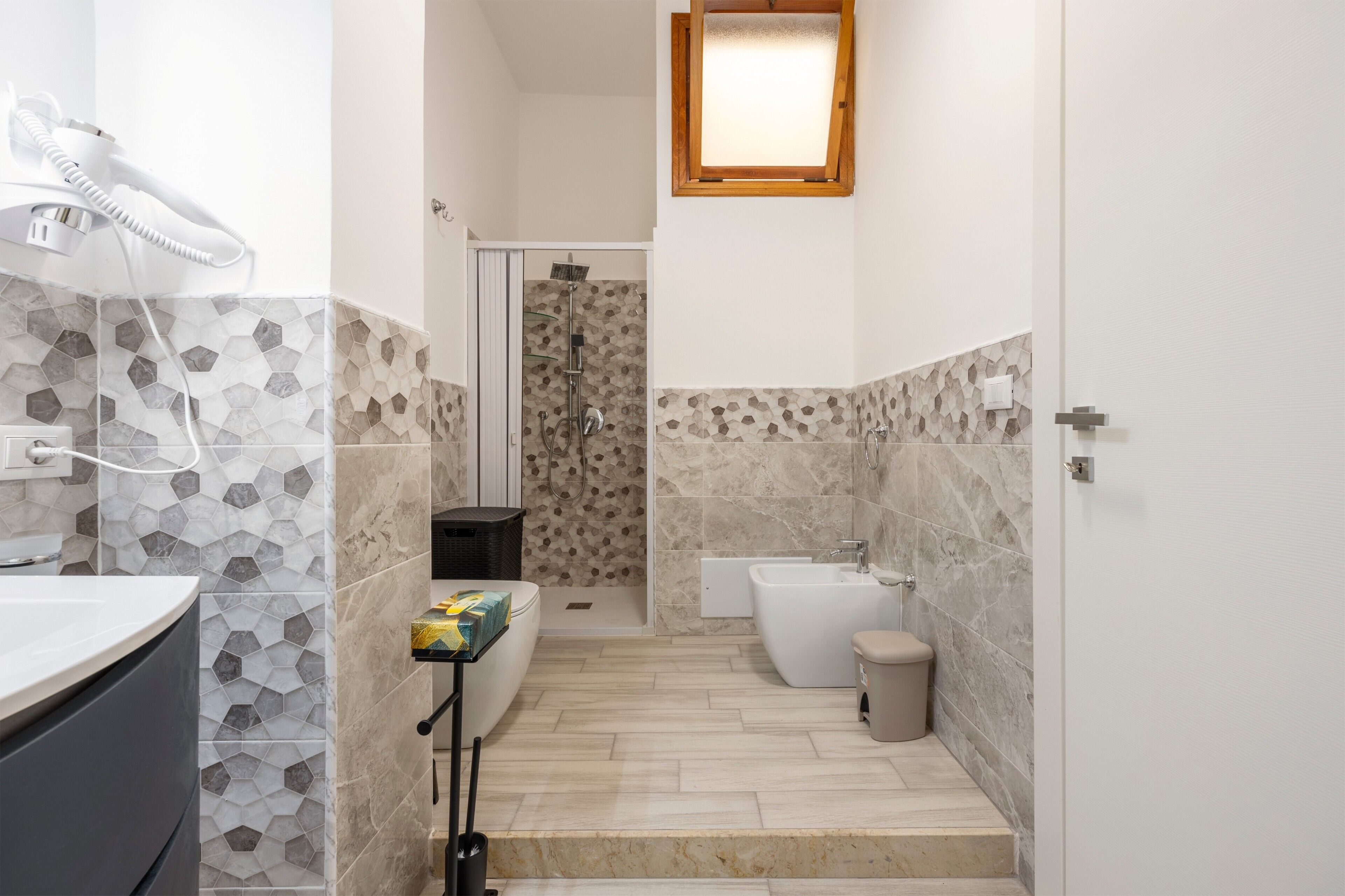 Une salle de bain équipée d’une douche, de toilettes, d’un bidet et d’un lavabo avec un porte-serviettes.