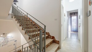 A staircase with a metal railing, a wall with a quote, and a hallway leading to a room with a patterned floor. - Guest House 'Sole e Amore' with Balcony, Wi-Fi and Air Conditioning (Casteldaccia)