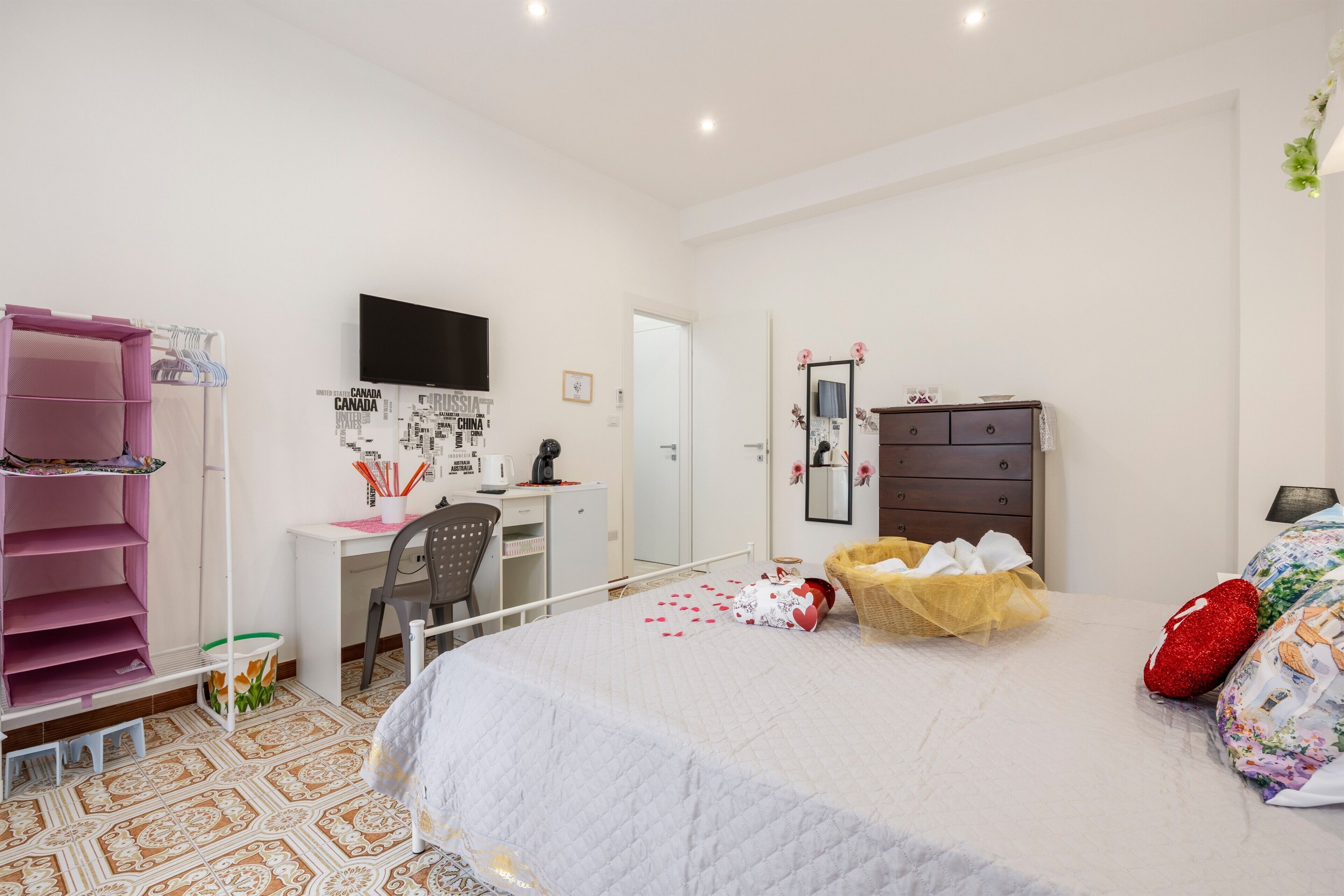 Una camera da letto con un letto, una scrivania, una sedia, un armadio e una libreria rosa.