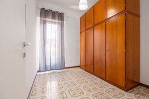 A room with patterned floor tiles, a wooden wardrobe, and a window with a curtain. - Guest House 'Sole e Amore' with Balcony, Wi-Fi and Air Conditioning (Casteldaccia)
