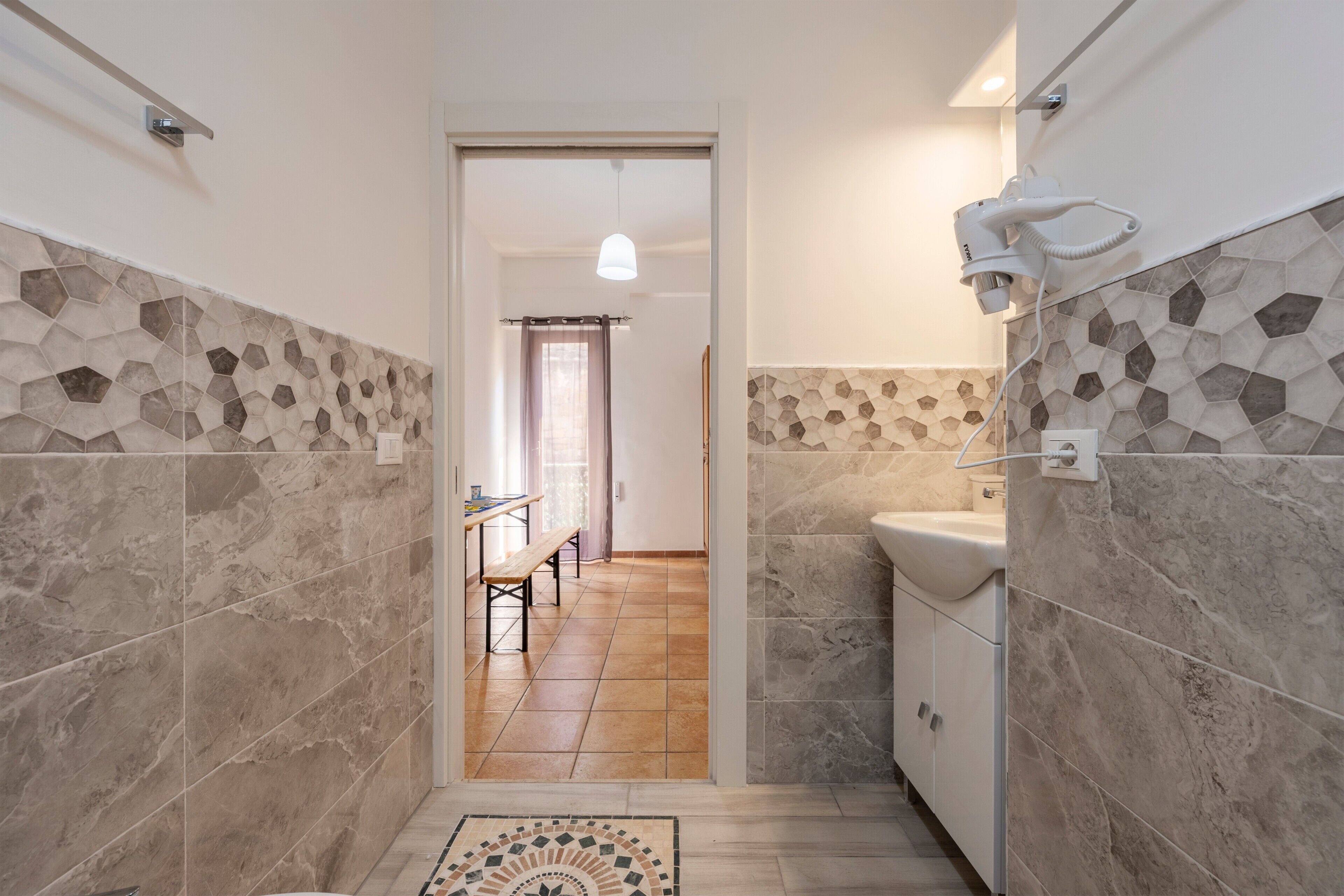 A bathroom with hexagonal patterned tiles, a sink, and a hairdryer.