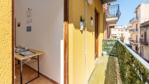 Un balcon doté d’un sol carrelé, d’une petite table sur laquelle repose un magazine et d’un luminaire fixé au mur.