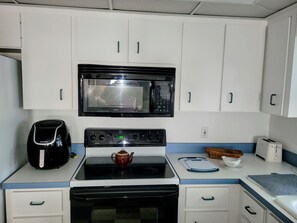 A compact kitchen with a microwave, stove, and a coffee maker.